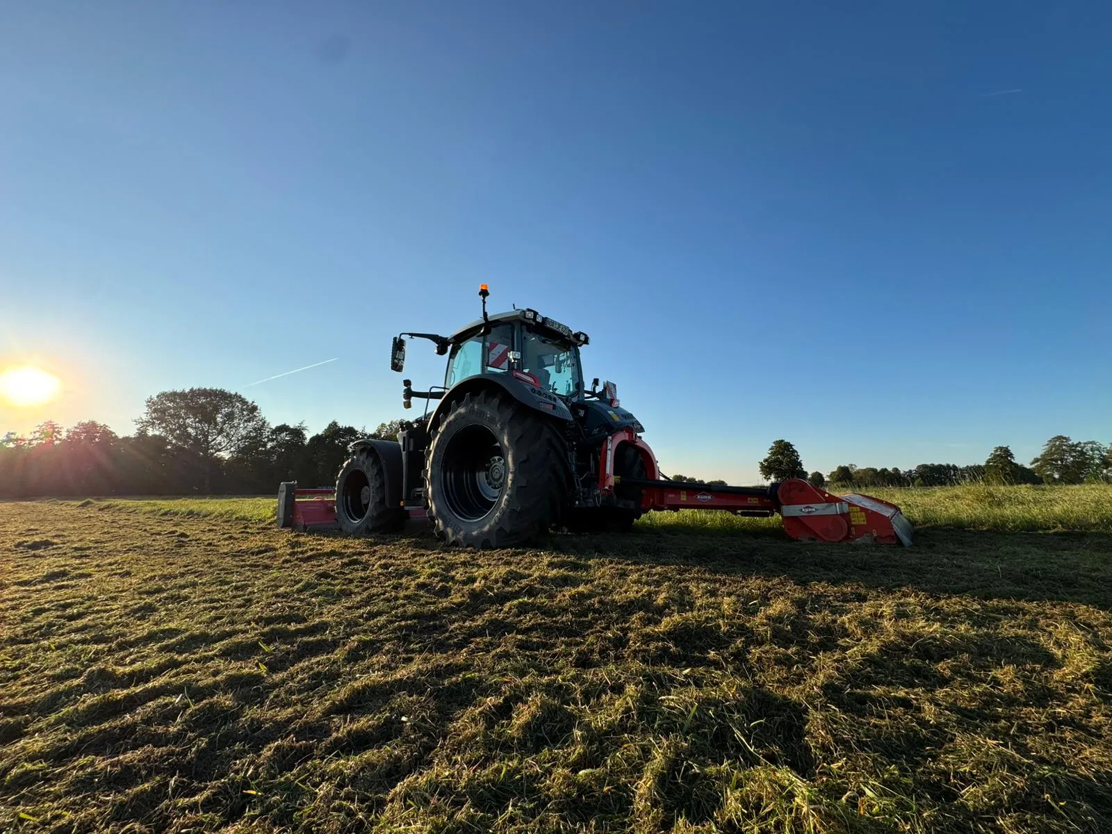 Traktor von JE Rent & Service bei der Feldarbeit im Abendlicht